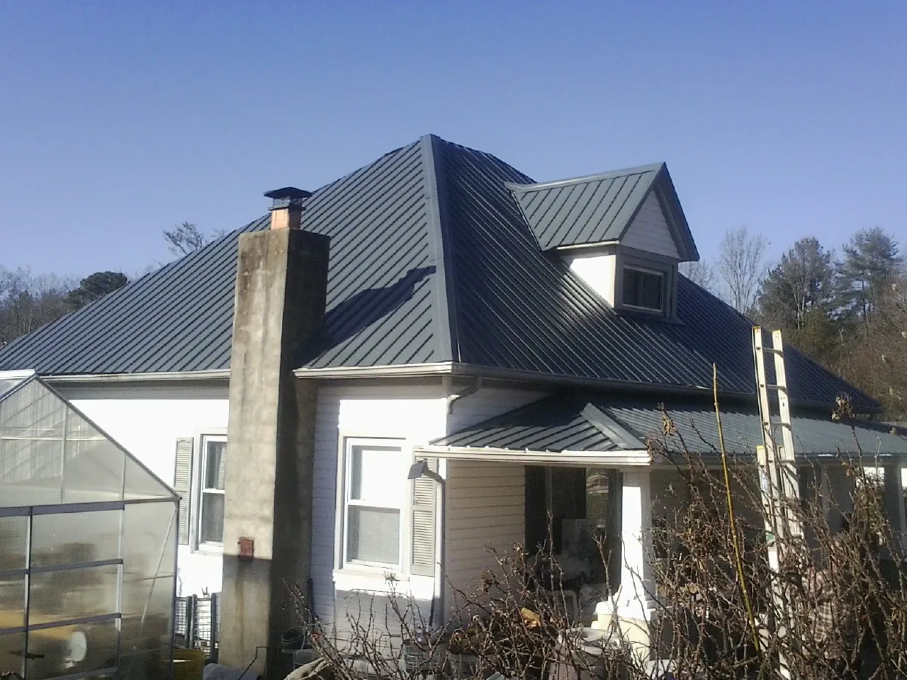 Dark blue standing seam metal roof on a white farmhouse with dormer — Slate & Tile Roof Repair by Roofing Brothers in Ulster