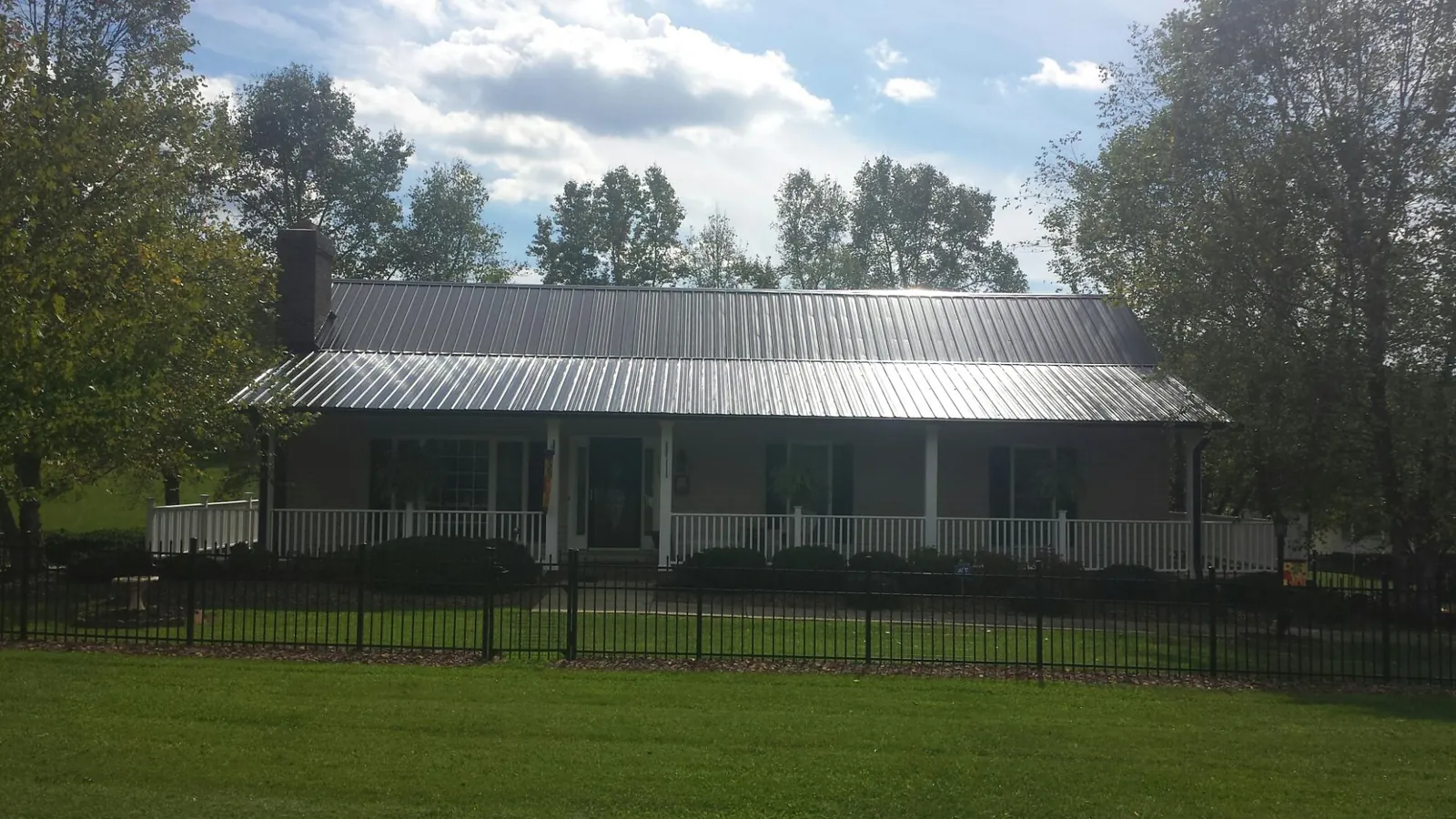 Gray metal roof on a brick ranch with a full width front porch — Gutter Guard Installation work by our crew in Ulster