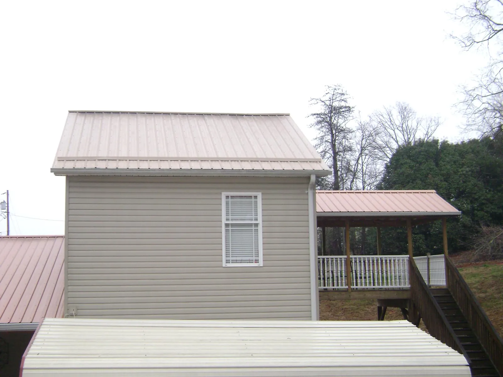 Tan metal roofs on a two story addition and attached porch, from a Roof Replacement job in Ulster