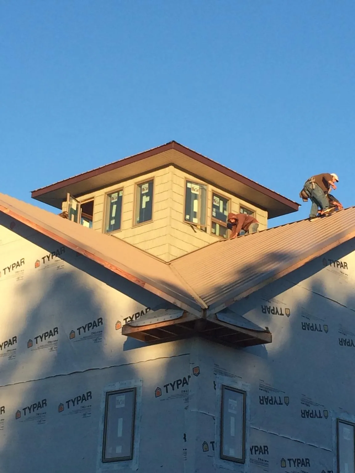 Roofers working around a rooftop cupola on a new metal roof at sunset — Roof Waterproofing in Ulster by Roofing Brothers
